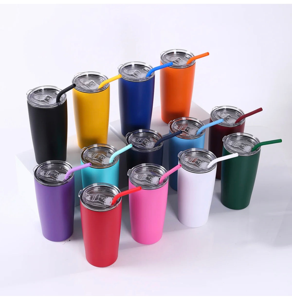 A group of insulated stainless steel travel tumblers with lids and straws, shown in multiple colors including black, yellow, blue, orange, pink, purple, teal, green, white, and red, arranged on a white background.