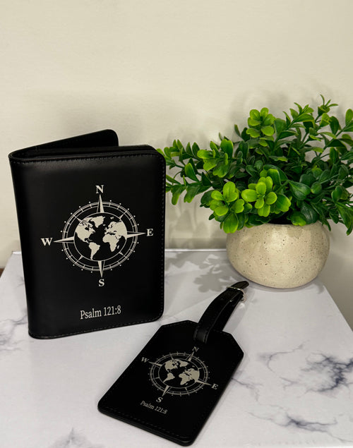 Black travel wallet and luggage tag with world map design on a marble surface with a plant.
